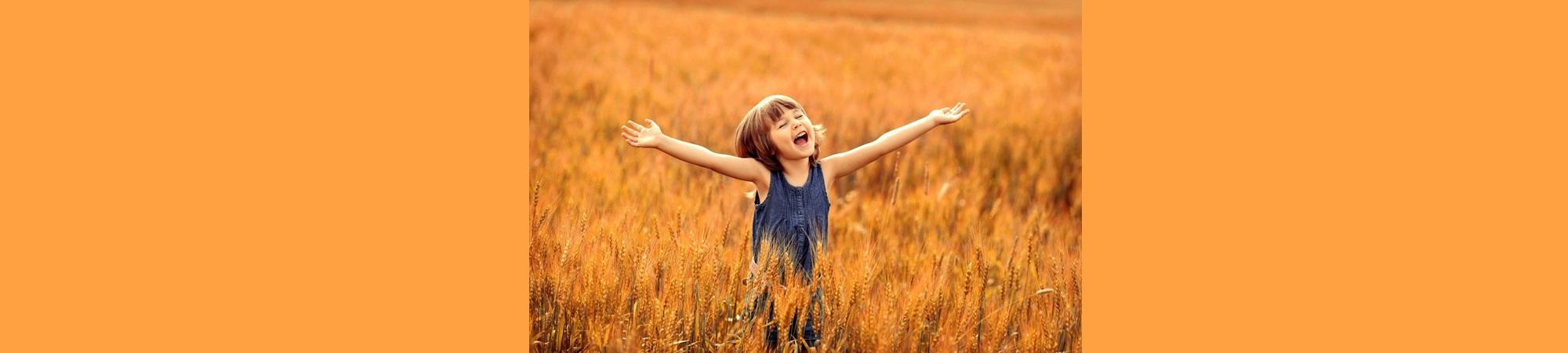 Delighted girl child in wheat field with arms outstretched